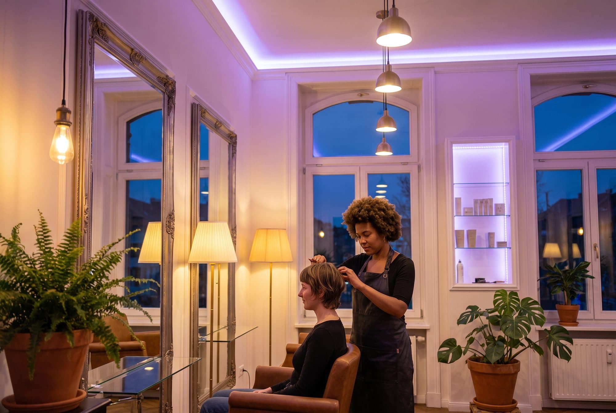 Frizerka ureja lase stranki v svetlem salonu z rastlinami